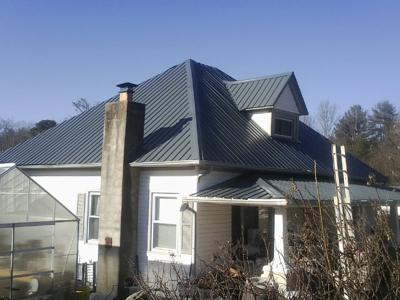 Dark blue standing seam metal roof on a white farmhouse with dormer — Slate & Tile Roof Repair by Roofing Brothers in Chadds Ford