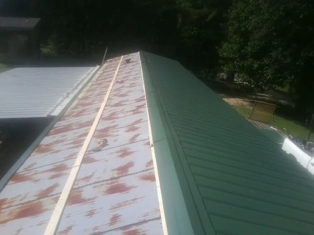 Old rusted panels beside newly installed green metal roofing — Wind Damage Roof Repair by Roofing Brothers in Chadds Ford