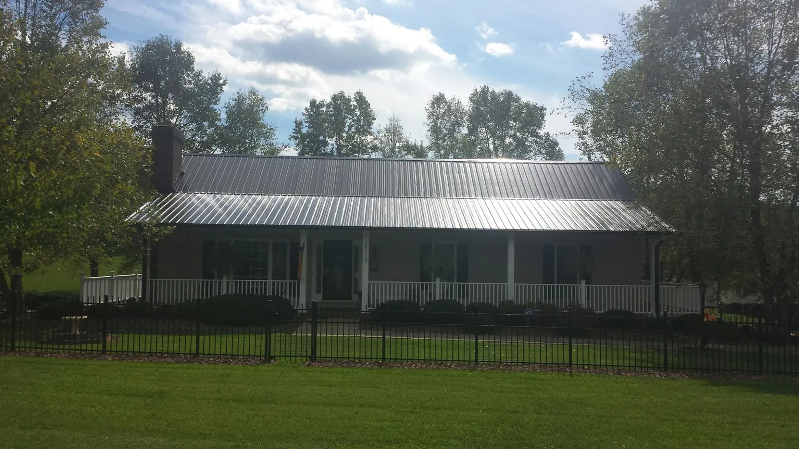 Gray metal roof on a brick ranch with a full width front porch — Gutter Guard Installation work by our crew in Chadds Ford
