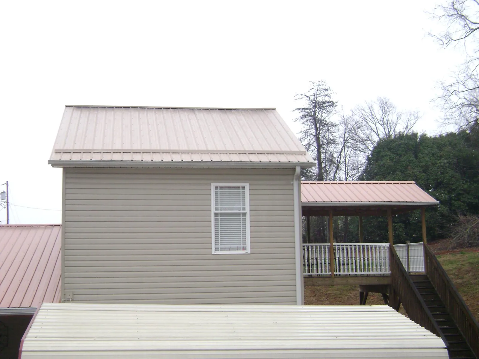 Tan metal roofs on a two story addition and attached porch, from a Roof Replacement job in Chadds Ford