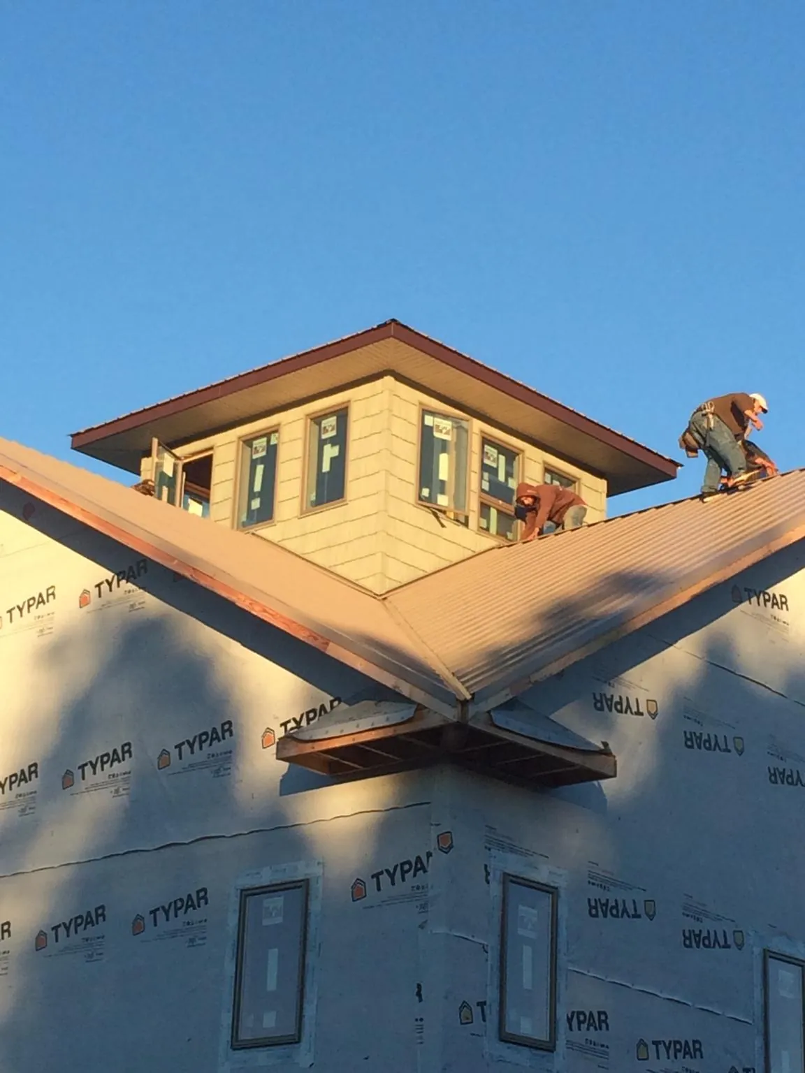 Roofers working around a rooftop cupola on a new metal roof at sunset — Roof Waterproofing in Chadds Ford by Roofing Brothers